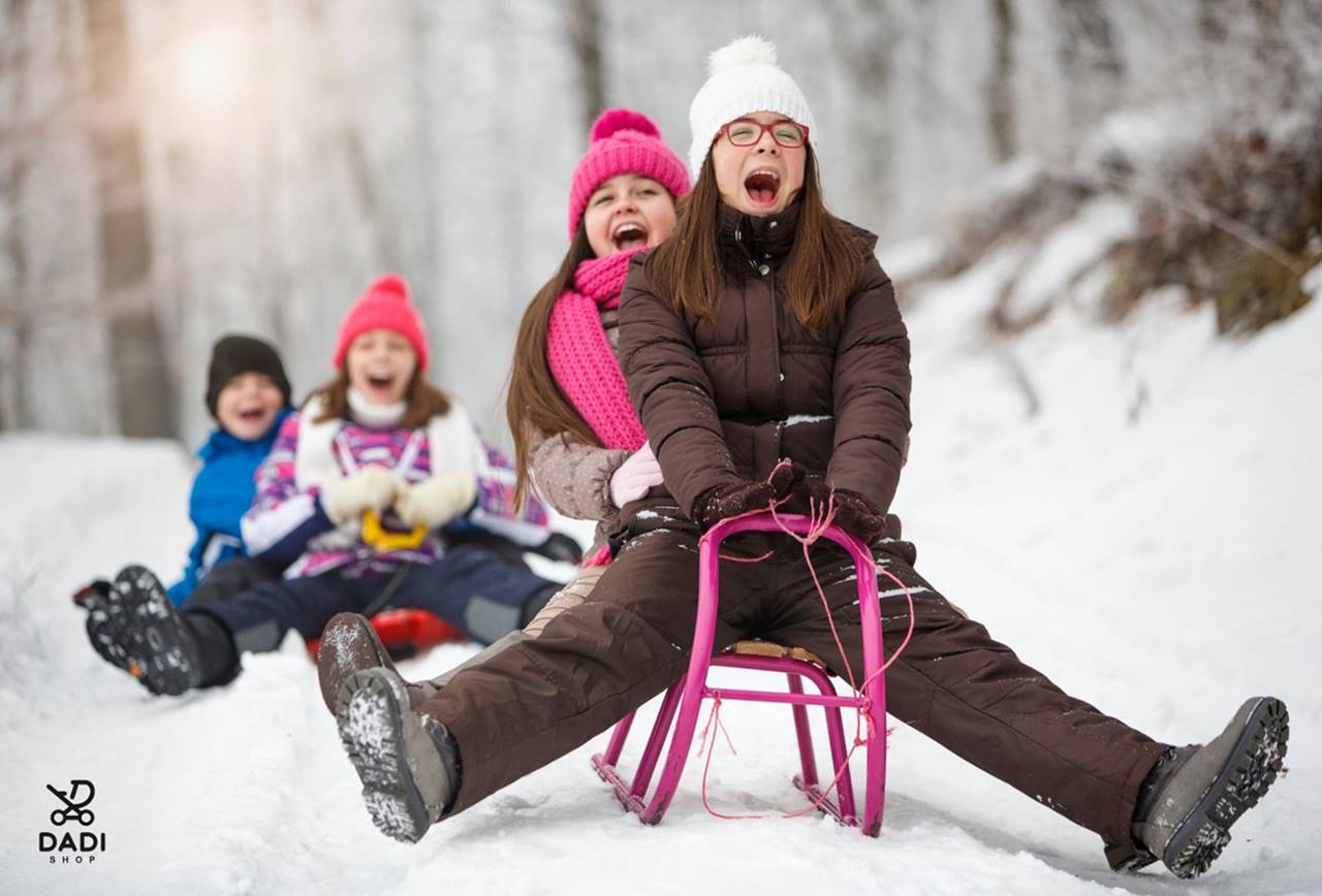 Dzieci bawią się na świeżym powietrzu, zjeżdżając na sankach – zabawa i hartowanie zimą.